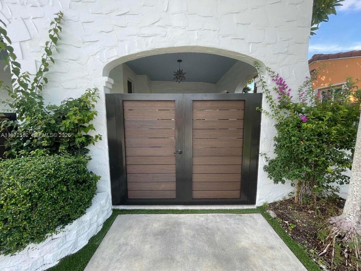 A double gate with horizontal wood slats is set within a white arched entryway — 5648 SW 5th Ter, Miami FL 33134, MIAMI, FL