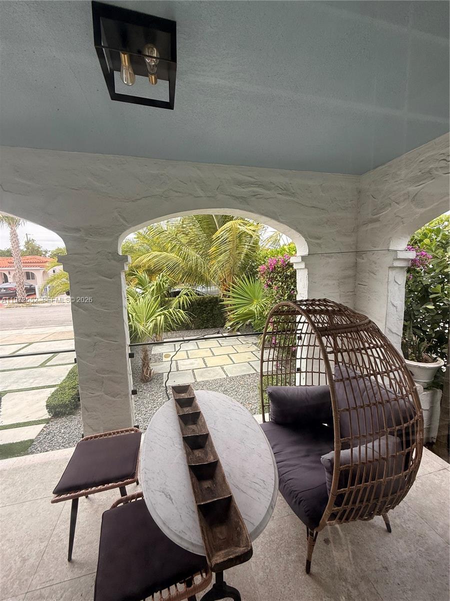 A covered patio features a marble-topped table, a wicker egg chair, and arched stone openings — 5648 SW 5th Ter, Miami FL 33134, MIAMI, FL