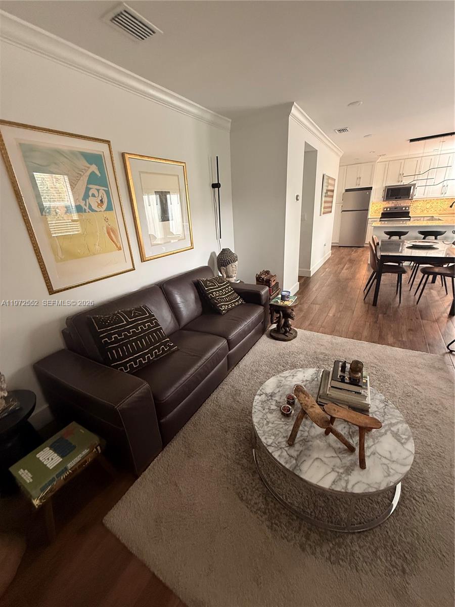 A living room with a brown leather sofa, marble coffee table, and adjacent kitchen area — 5648 SW 5th Ter, Miami FL 33134, MIAMI, FL