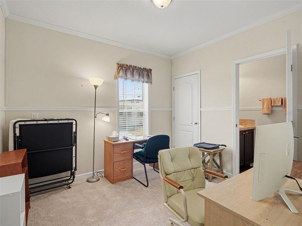 A home office features a desk, two chairs, a floor lamp, and an attached bathroom — 312 52ND AVENUE W, BRADENTON, FL
