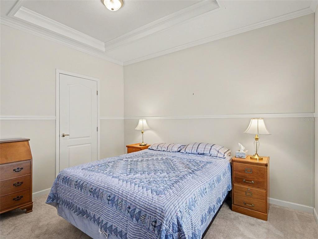 A bedroom features a bed with a blue quilt, two nightstands, and a wooden dresser — 312 52ND AVENUE W, BRADENTON, FL
