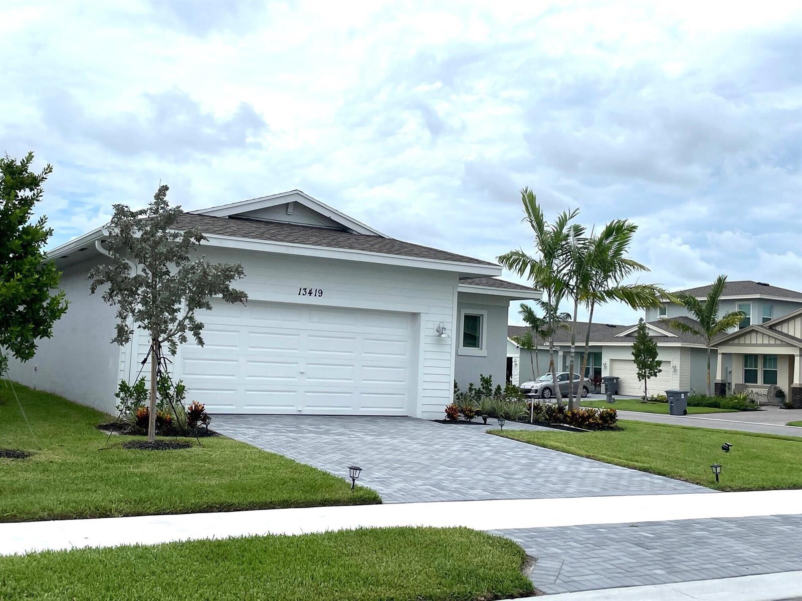 A single-story house with a white garage, gray paver driveway, and palm trees — 13419 Noble Drive, Delray Beach FL 33484, DELRAY BEACH, FL