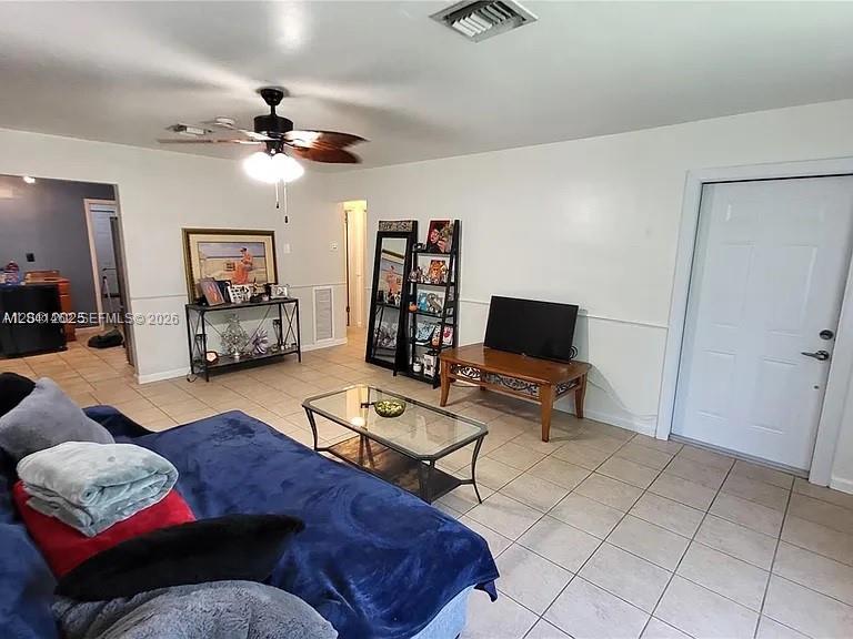A living room features a blue sofa, a glass coffee table, and a ceiling fan — 124 NW 6th Ave, Hallandale Beach FL 33009, HALLANDALE BEACH, FL