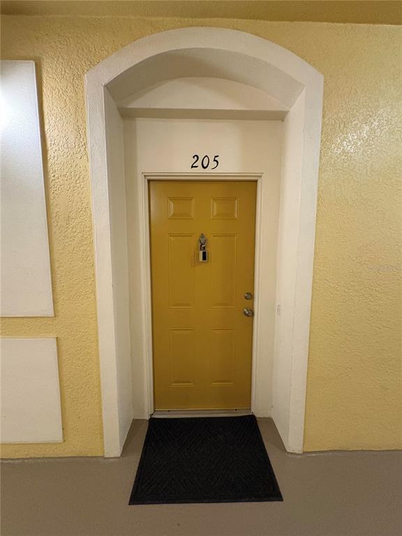 A yellow door with a lockbox and the number 205 sits within an arched entryway — 3314 ROBERT TRENT JONES DRIVE UNIT 20501, ORLANDO, FL
