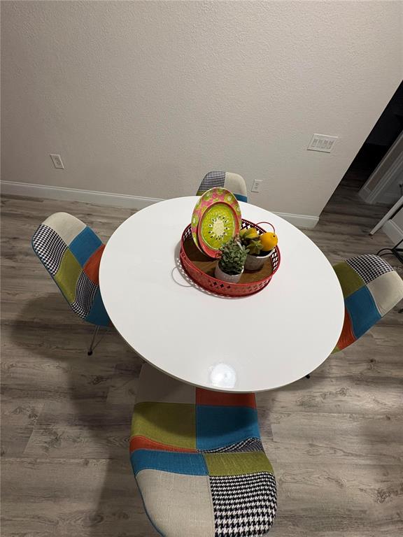 A small white round table is surrounded by four colorful patchwork chairs on wood flooring — 3314 ROBERT TRENT JONES DRIVE UNIT 20501, ORLANDO, FL