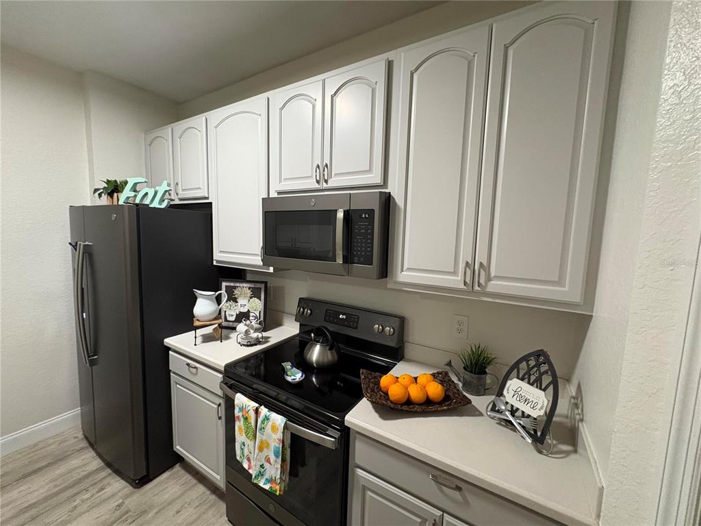 A kitchen features white cabinets, a black refrigerator, a microwave, and a black electric stove — 3314 ROBERT TRENT JONES DRIVE UNIT 20501, ORLANDO, FL