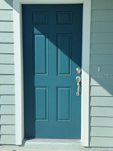 A teal six-panel front door is set within light blue horizontal siding — 127 CAMPHOR LAUREL ROAD, ST AUGUSTINE, FL