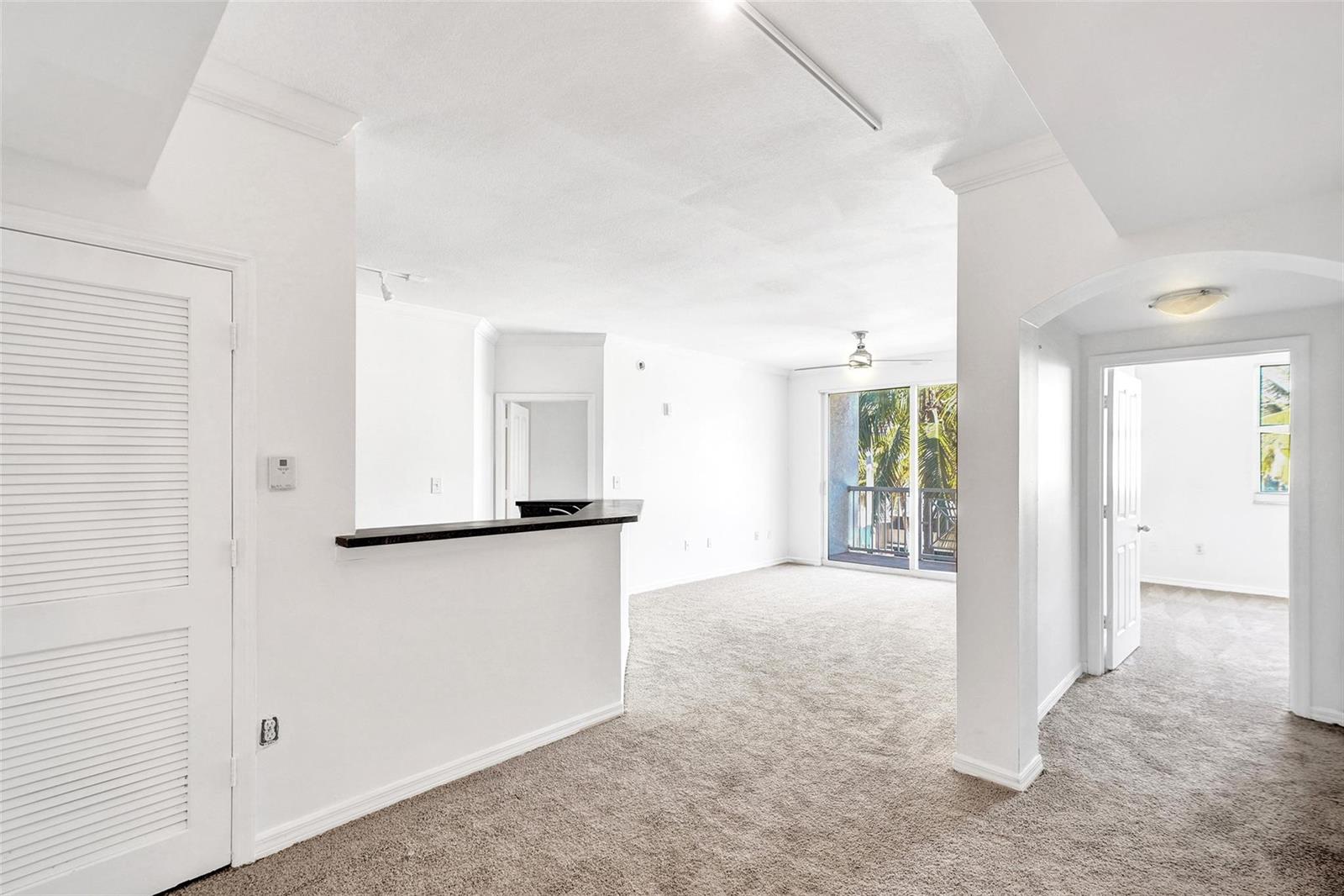 An interior view of a carpeted living area with a breakfast bar and balcony access — 9172 Collins Avenue # 302, Surfside FL 33154, SURFSIDE, FL