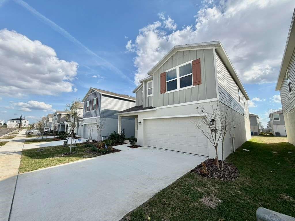 A two-story house with a light-colored stucco garage and gray vertical siding on the upper level — 3638 HARDMAN DRIVE, LAKE WALES, FL