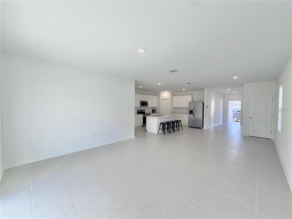 An open-concept kitchen with a central island and white cabinets overlooks a tiled living area — 3638 HARDMAN DRIVE, LAKE WALES, FL