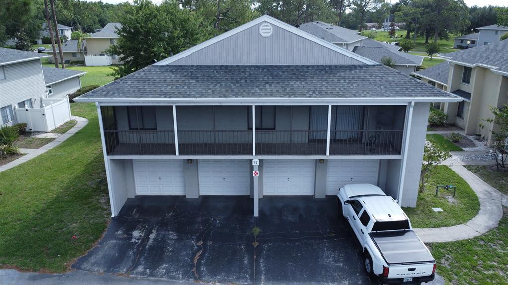 An aerial view of a two-story residential building with four garage doors and a balcony — 4323 PINEBARK AVENUE UNIT 77-1, ORLANDO, FL