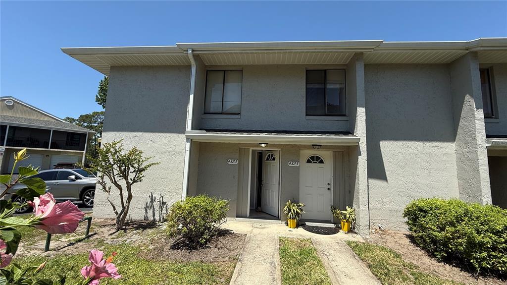 The exterior of a two-story townhouse features light-colored stucco walls and two adjacent front doors — 4323 PINEBARK AVENUE UNIT 77-1, ORLANDO, FL