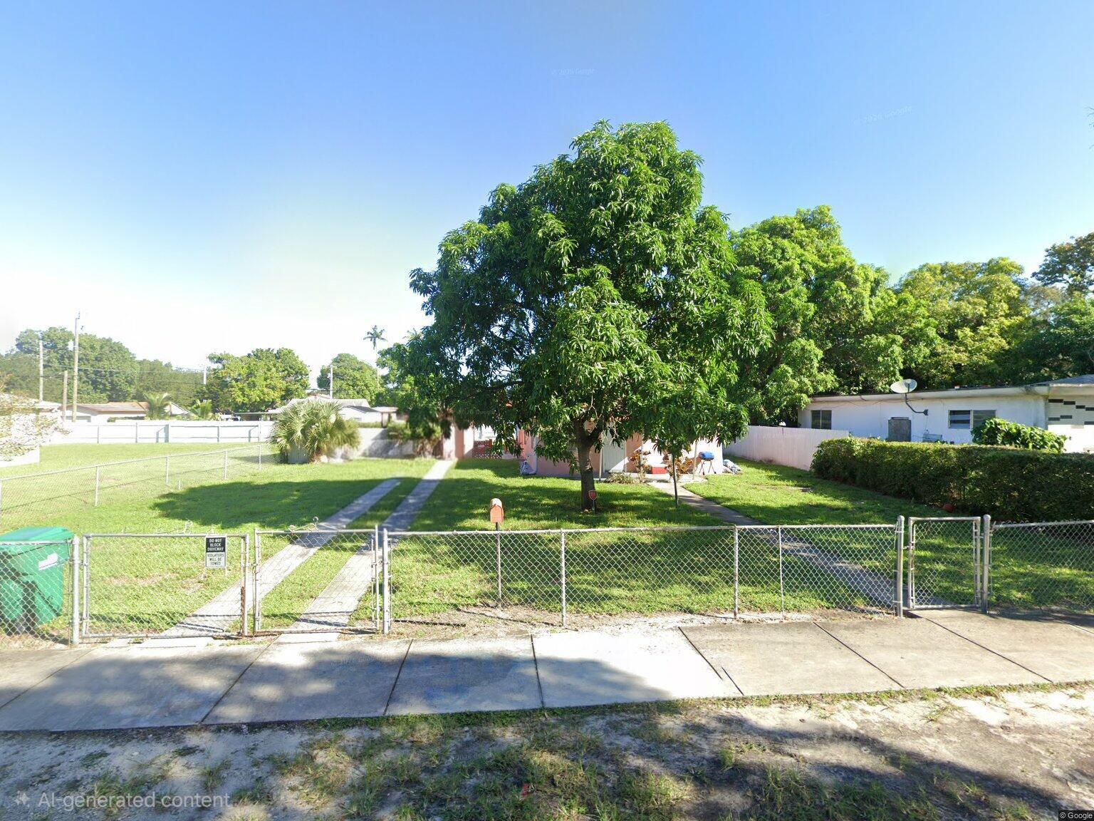 A chain-link fence encloses a front yard with a large tree and a driveway — 2467 NW 90th Street, Miami FL 33147, MIAMI, FL