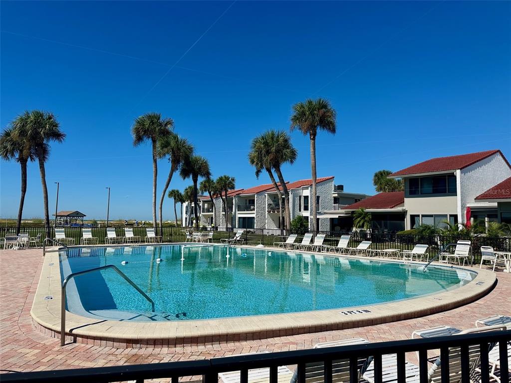 A swimming pool sits on a brick patio surrounded by palm trees and apartment buildings — 500 PARK BOULEVARD S UNIT 46, VENICE, FL