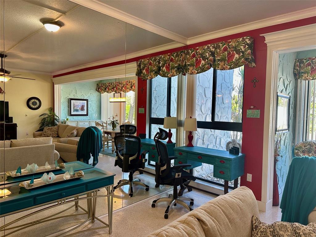 A living room features a teal desk, a mirrored wall, and a red accent wall — 500 PARK BOULEVARD S UNIT 46, VENICE, FL