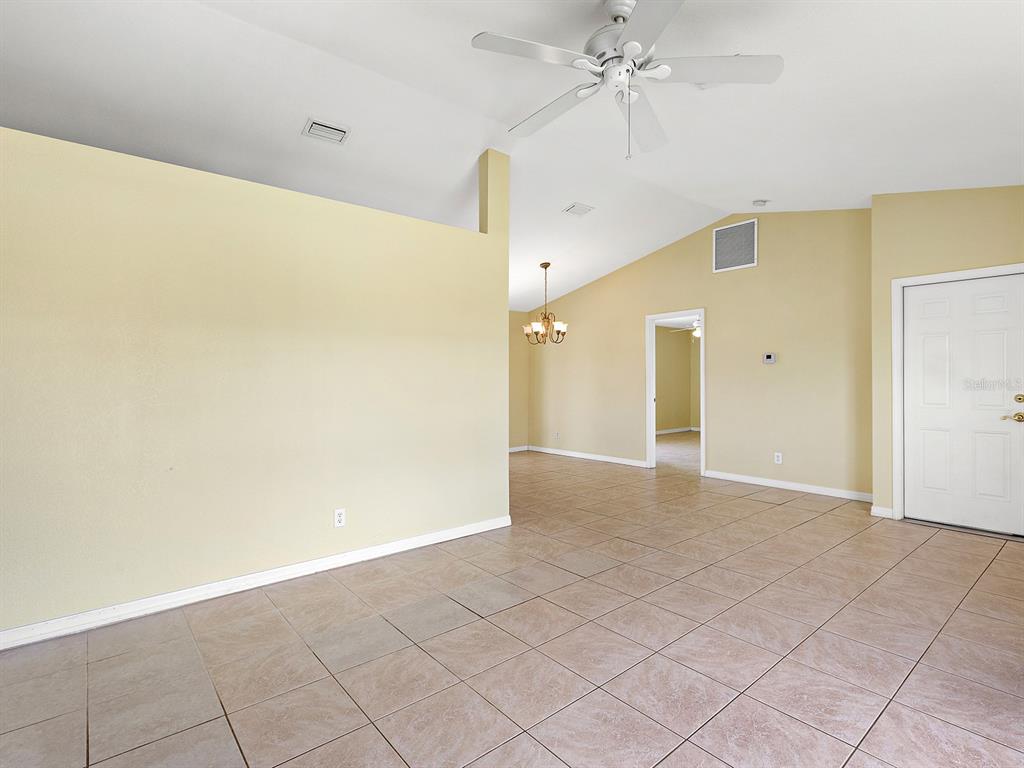 An interior view of a room with beige walls, tile flooring, and a ceiling fan — 12404 WILLMINGTON BOULEVARD, PORT CHARLOTTE, FL