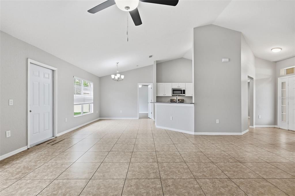 An open-concept living and dining area features light gray walls and beige tile flooring — 2442 AMBASSADOR AVENUE, SPRING HILL, FL