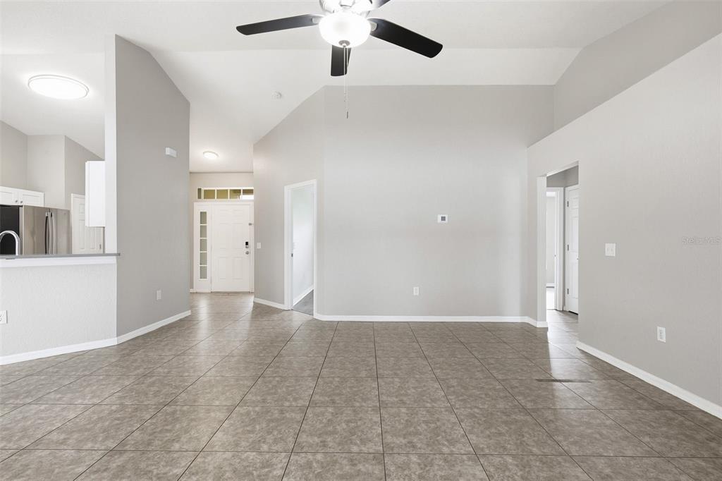 An open-concept living area features light gray walls, tile flooring, and a vaulted ceiling — 2442 AMBASSADOR AVENUE, SPRING HILL, FL