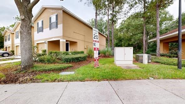 A two-story tan apartment building with a speed limit sign in the front yard — 4104 WINDING RIVER WAY, LAND O LAKES, FL