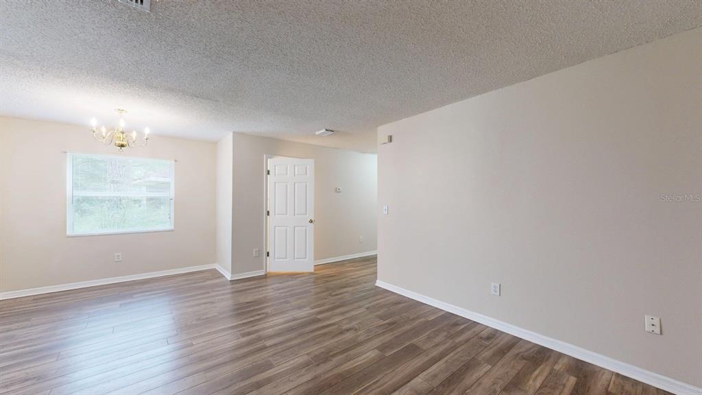 An empty room features light-colored walls, wood-look flooring, a ceiling fan, and a white door — 4104 WINDING RIVER WAY, LAND O LAKES, FL