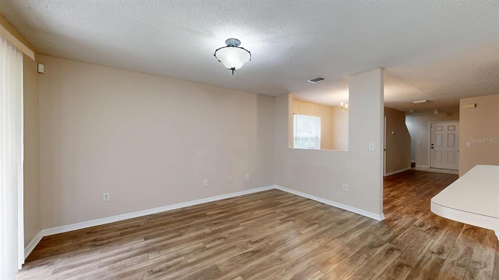 An empty room with wood-look flooring, beige walls, and a ceiling light fixture — 4104 WINDING RIVER WAY, LAND O LAKES, FL