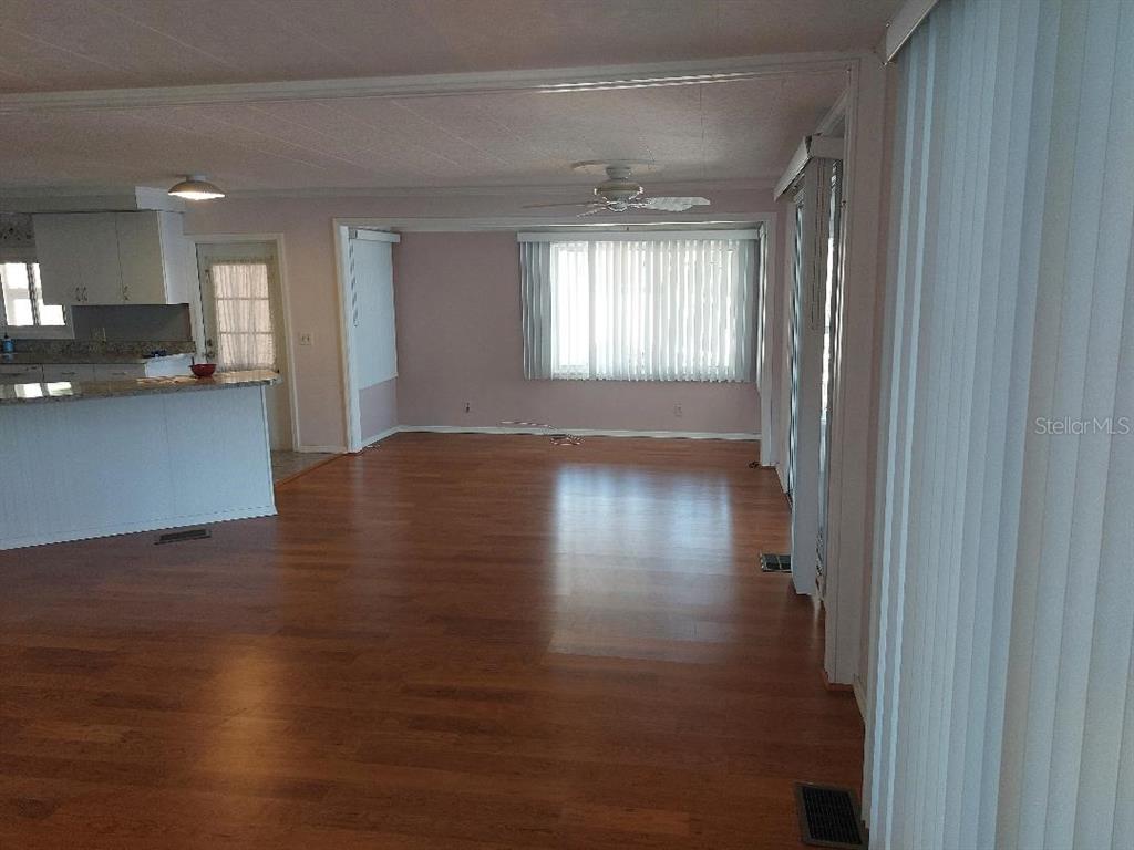 An open-concept living area features light-colored walls, wood-look flooring, and a kitchen island — 272 PHILADELPHIA BOULEVARD UNIT 48, PALM HARBOR, FL