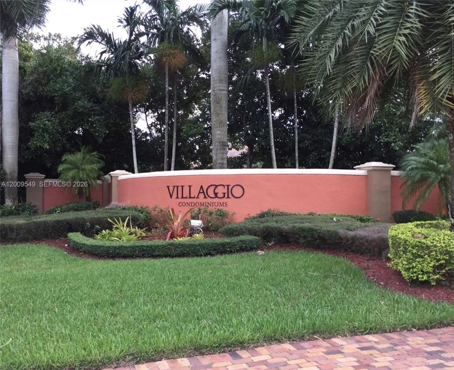 A curved, peach-colored wall displays the name Villaggio Condominiums amidst palm trees and landscaping — 4404 SW 160th Ave # 832, Miramar FL 33027, MIRAMAR, FL
