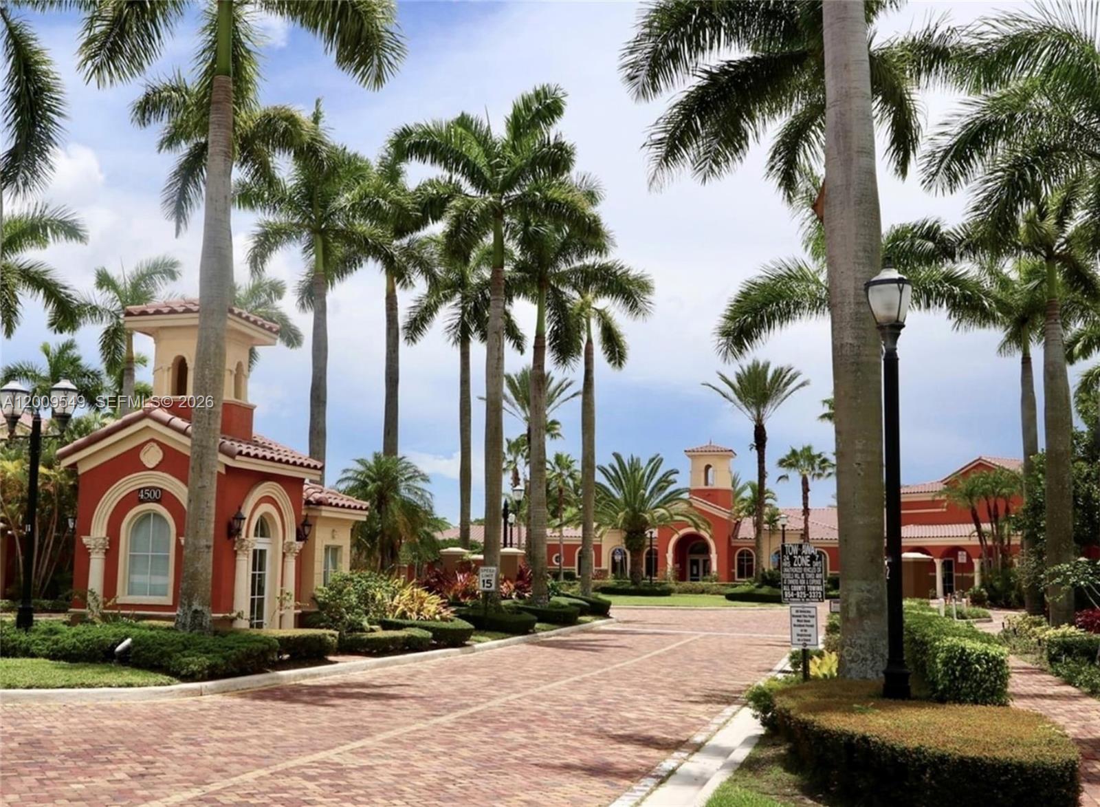 A brick driveway leads toward a Mediterranean-style building entrance surrounded by tall palm trees — 4404 SW 160th Ave # 832, Miramar FL 33027, MIRAMAR, FL