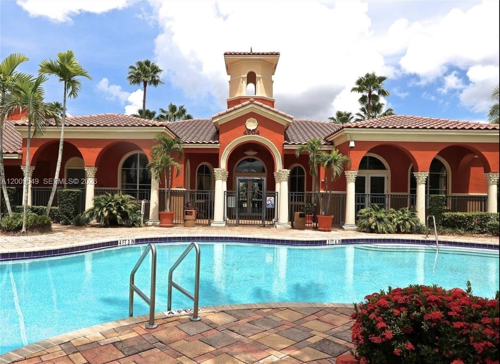 A swimming pool sits in front of a Mediterranean-style clubhouse with arched entryways and columns — 4404 SW 160th Ave # 832, Miramar FL 33027, MIRAMAR, FL