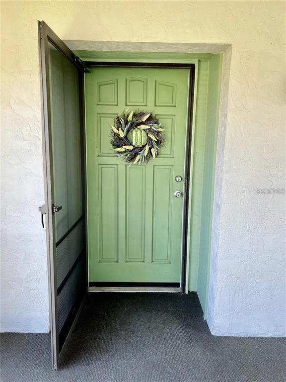 A green front door with a wreath stands open behind a metal screen door — 3504 BENEVA ROAD UNIT 206, SARASOTA, FL
