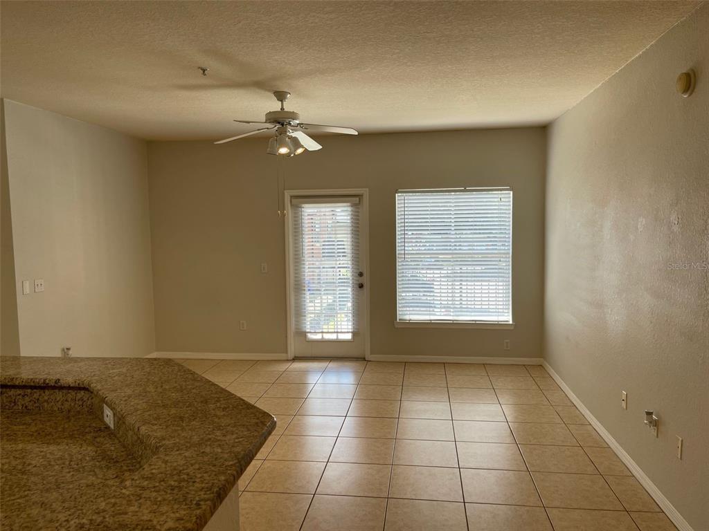An empty room with beige tile flooring, a ceiling fan, and a glass door — 5959 WESTGATE DRIVE UNIT 1526, ORLANDO, FL