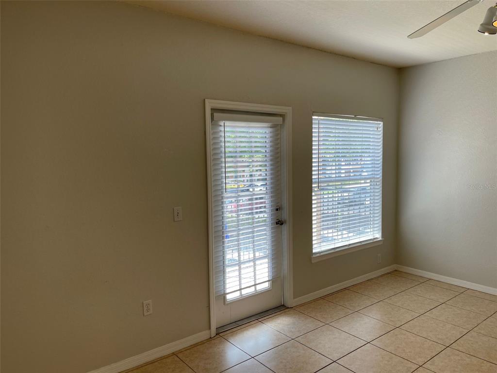 An empty room with beige walls, tile flooring, a glass door, and a window — 5959 WESTGATE DRIVE UNIT 1526, ORLANDO, FL