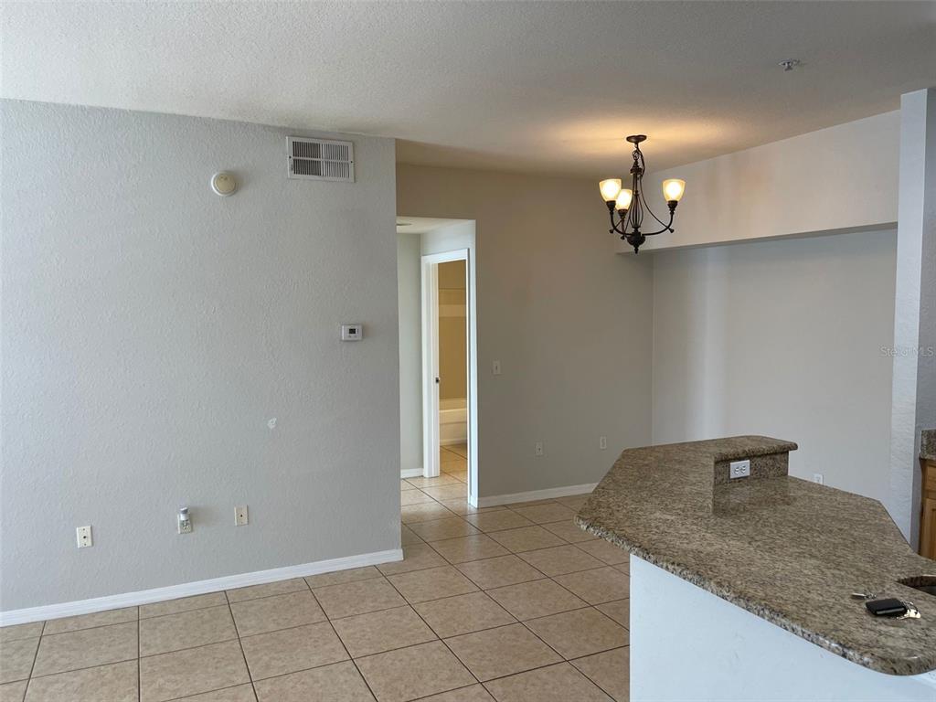 An interior view showing a tiled kitchen area with a granite countertop and dining chandelier — 5959 WESTGATE DRIVE UNIT 1526, ORLANDO, FL