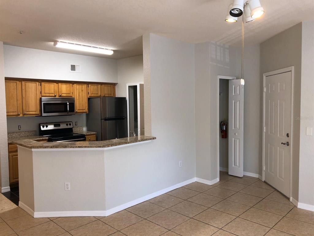 A kitchen with wood cabinets, stainless steel appliances, and a granite breakfast bar — 5959 WESTGATE DRIVE UNIT 1526, ORLANDO, FL