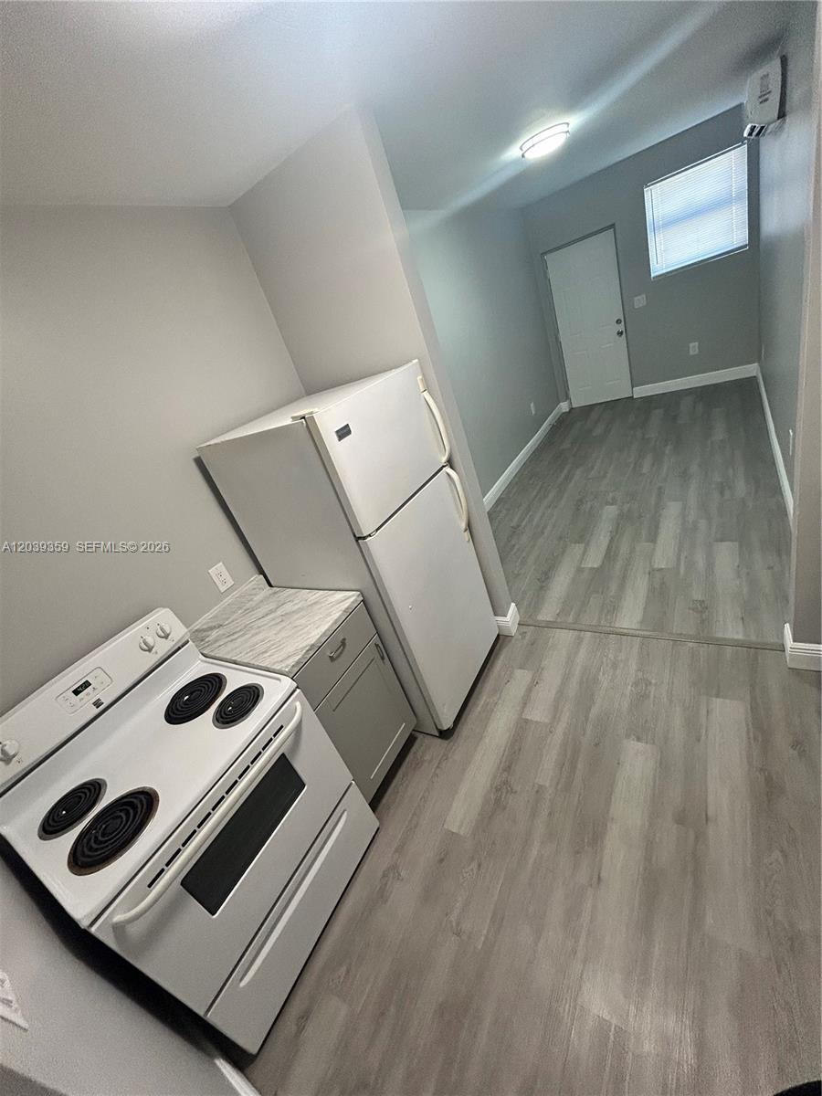 A small kitchen area features a white stove, a white refrigerator, and gray flooring — 1740 NW 1st Pl # 5, Miami FL 33136, MIAMI, FL