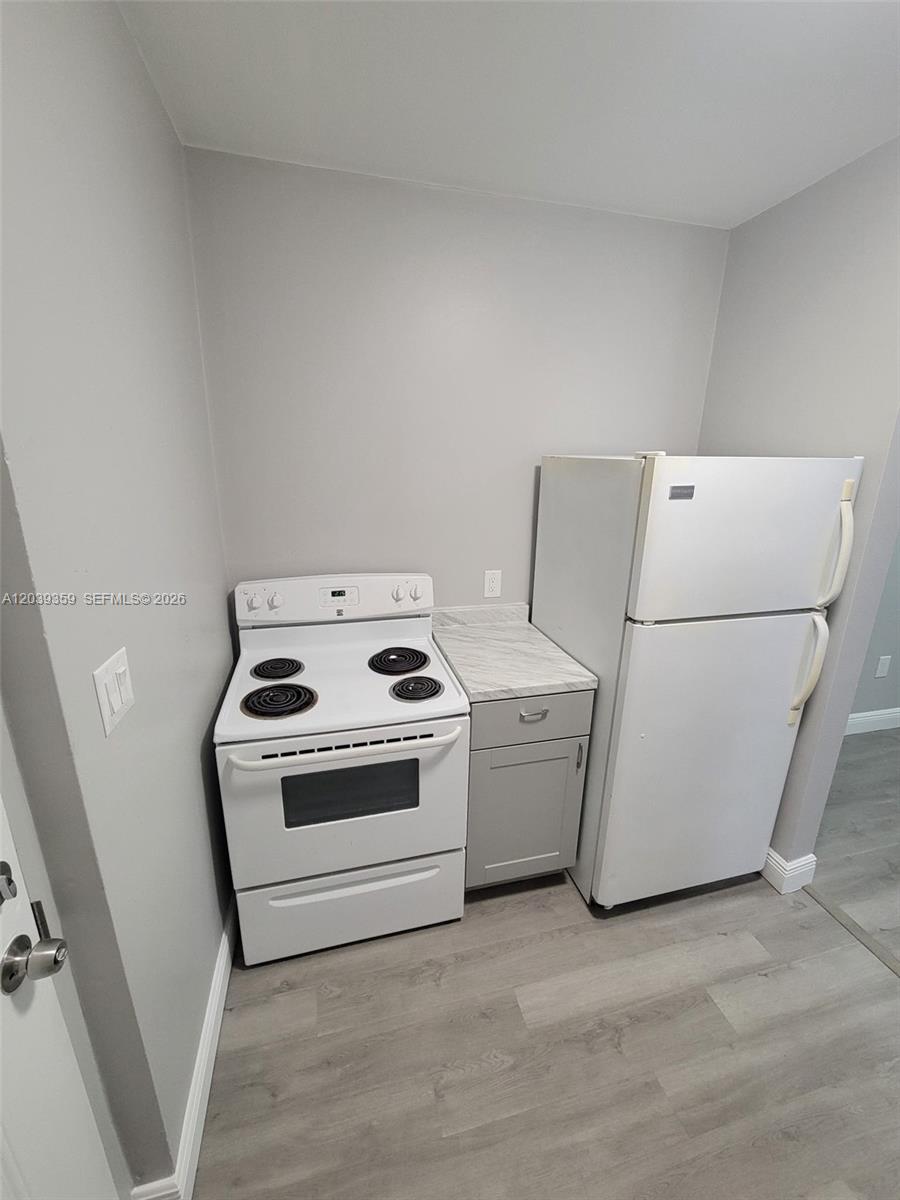 A small kitchen features a white electric stove, a white refrigerator, and a single cabinet — 1740 NW 1st Pl # 5, Miami FL 33136, MIAMI, FL