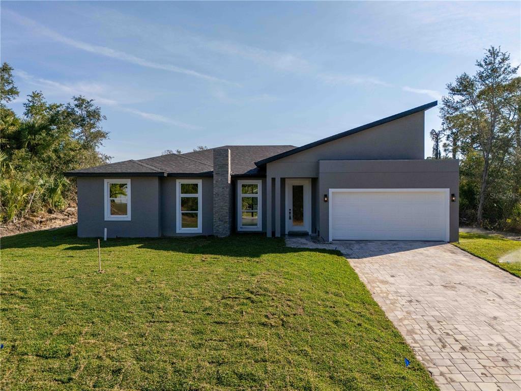 A modern single-story house with a gray exterior, stone chimney, and a two-car garage — 70 MCDILL DRIVE, PORT CHARLOTTE, FL