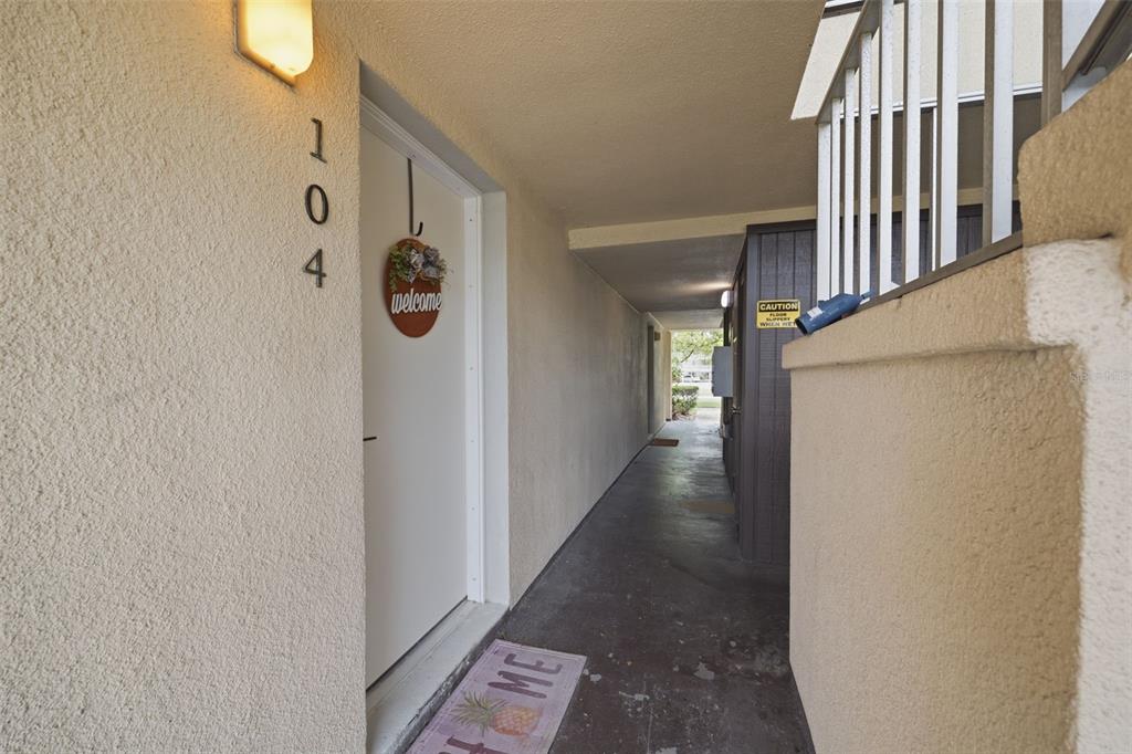 A covered exterior walkway leads to the entrance of a unit marked with number 104 — 5242 OPAL LANE UNIT 104, NEW PORT RICHEY, FL