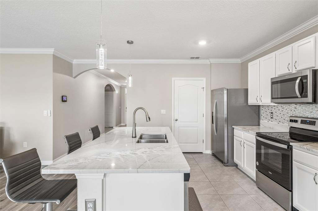 A kitchen features a white marble island, stainless steel appliances, and white cabinetry — 109 SOFIA LANE, LAKE ALFRED, FL
