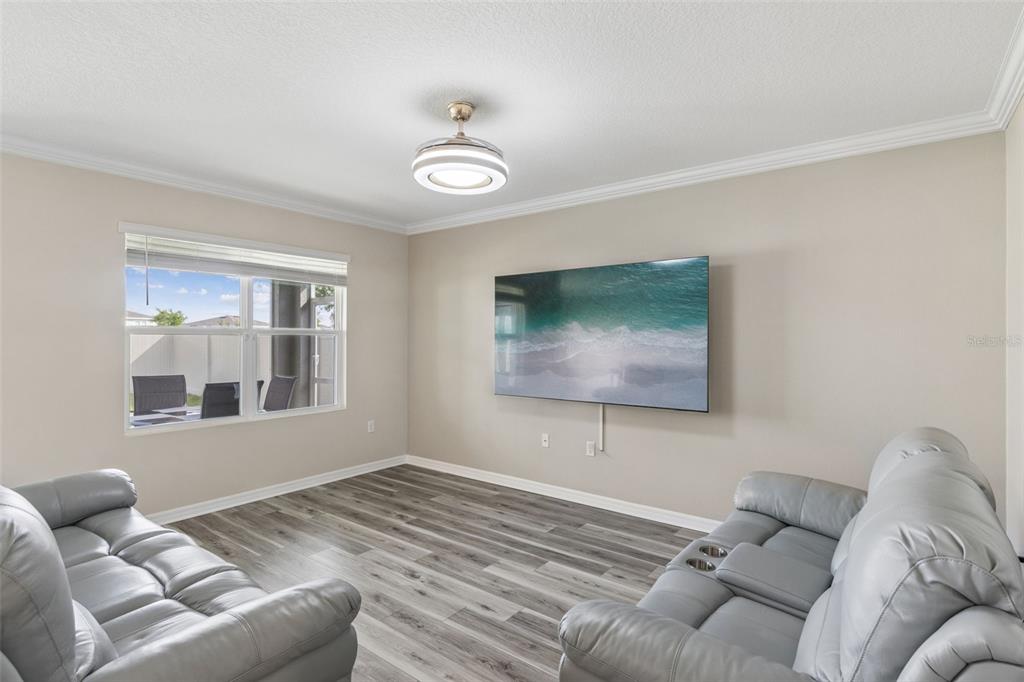 A living room features gray wood-look flooring, two gray leather sofas, and a wall-mounted television — 109 SOFIA LANE, LAKE ALFRED, FL