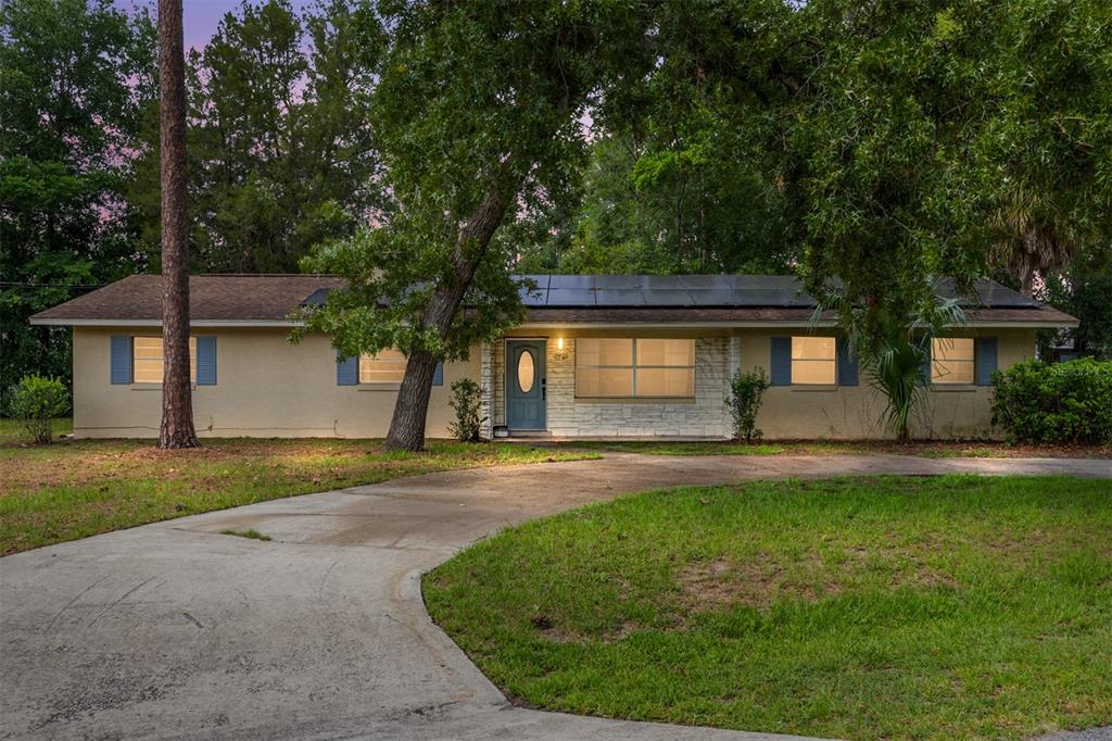 A single-story house with a curved driveway, solar panels on the roof, and stone accents — 1921 NE 49TH AVENUE, OCALA, FL