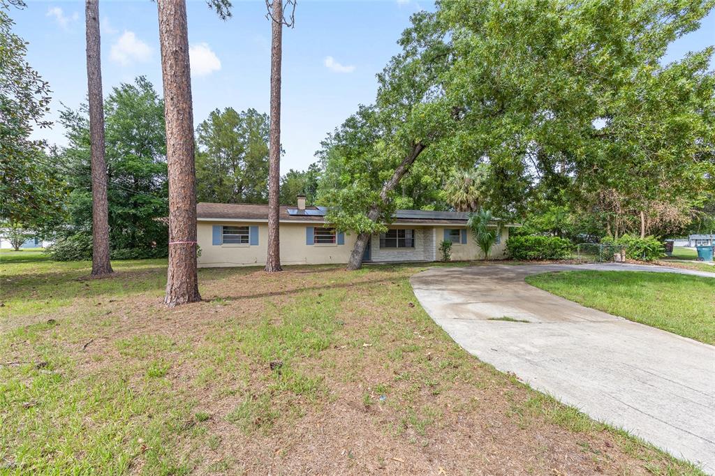 A single-story house with a concrete driveway sits on a grassy lot with trees — 1921 NE 49TH AVENUE, OCALA, FL