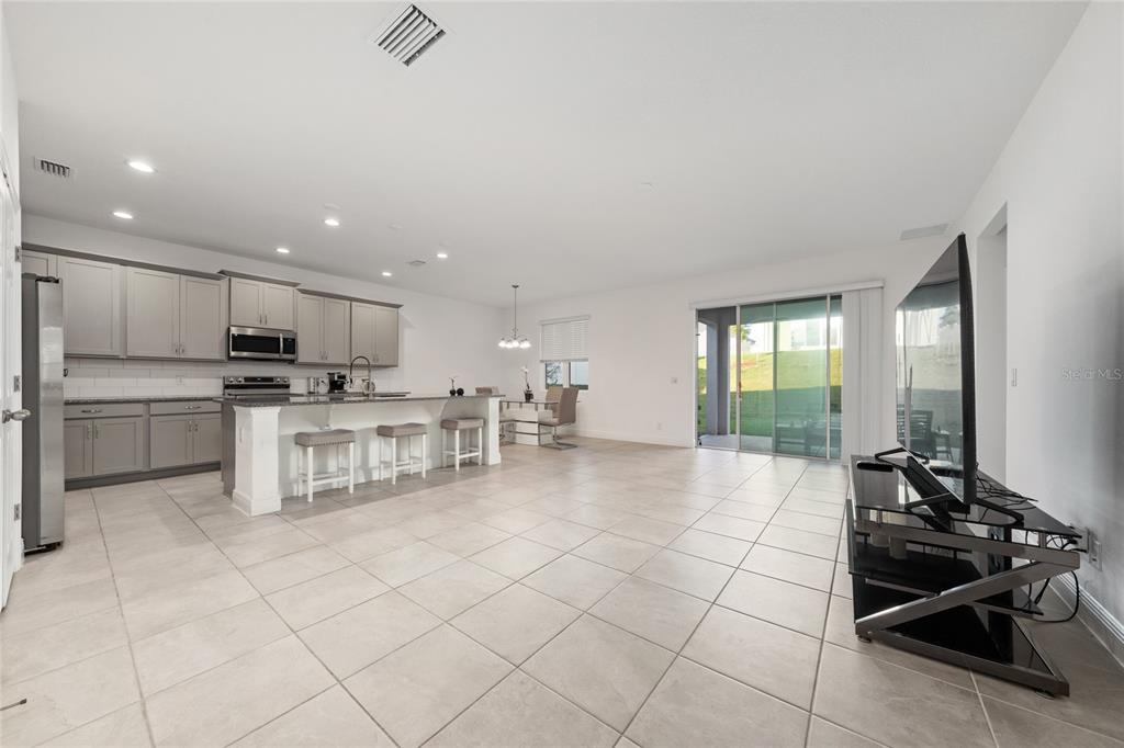 An open-concept kitchen and living area featuring grey cabinets, a breakfast bar, and tile flooring — 1867 LAKE INDIGO ROAD, GROVELAND, FL