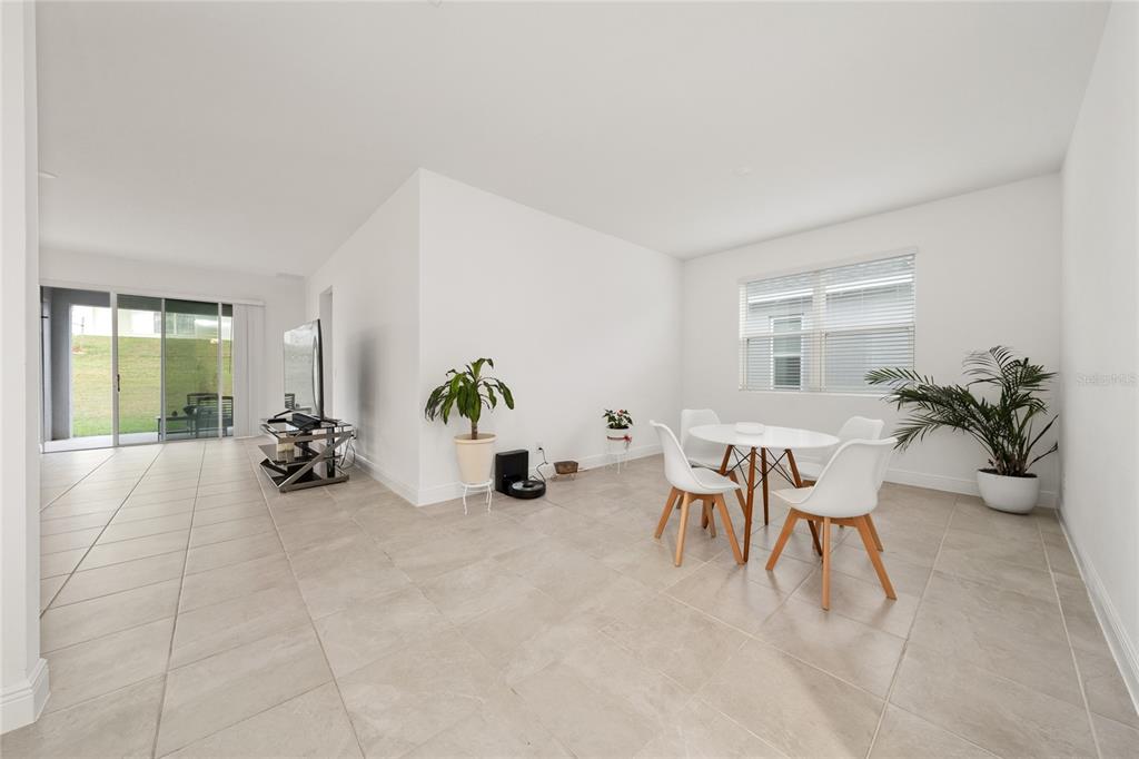A bright, open-concept dining area with white walls, tile flooring, and a sliding glass door — 1867 LAKE INDIGO ROAD, GROVELAND, FL