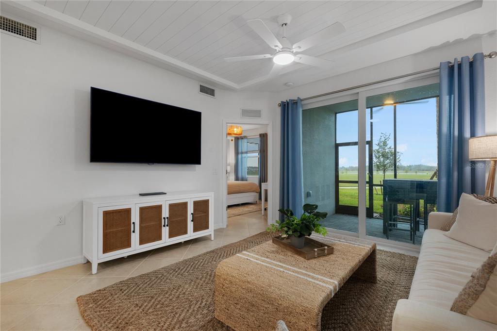 A living room features a white media console, a woven coffee table, and sliding glass doors — 17630 OPAL SAND DRIVE UNIT 108, VENICE, FL