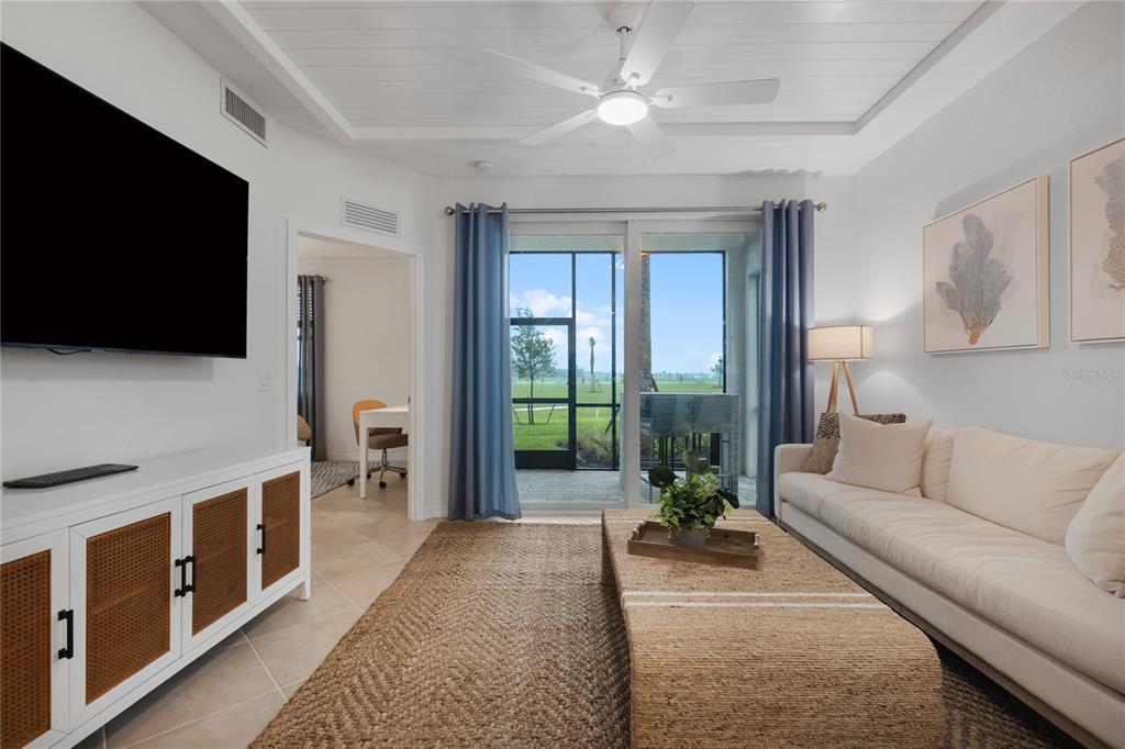 A living room features a white media console, a beige sofa, and a sliding glass door — 17630 OPAL SAND DRIVE UNIT 108, VENICE, FL