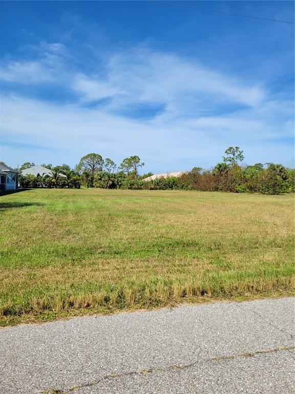 A vacant, grassy residential lot sits next to a house under a clear blue sky — 9 HYDE COURT, ROTONDA WEST, FL