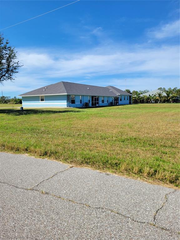 A light blue, single-story house with a dark shingled roof sits on a grassy lot — 9 HYDE COURT, ROTONDA WEST, FL