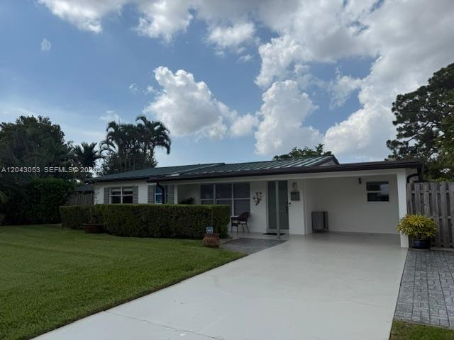 A single-story house features a white exterior, a metal roof, and a paved driveway — 330 NE 48th St, Oakland Park FL 33334, OAKLAND PARK, FL