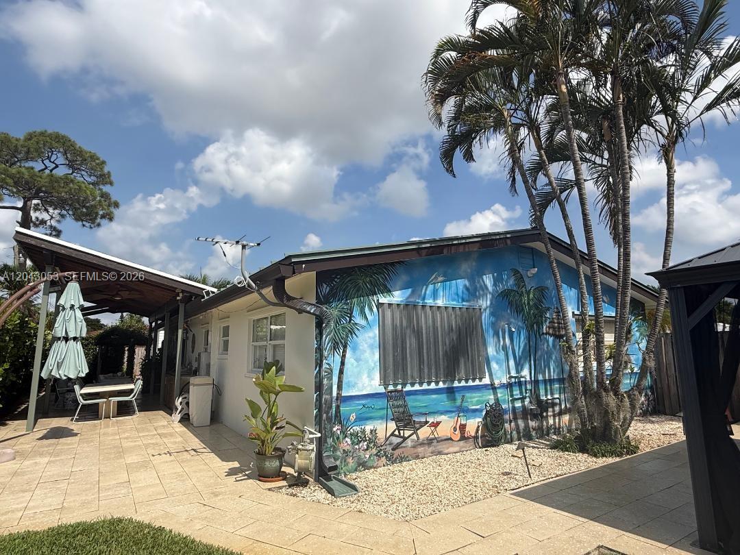 A house exterior features a large beach-themed mural on the side wall and a patio — 330 NE 48th St, Oakland Park FL 33334, OAKLAND PARK, FL